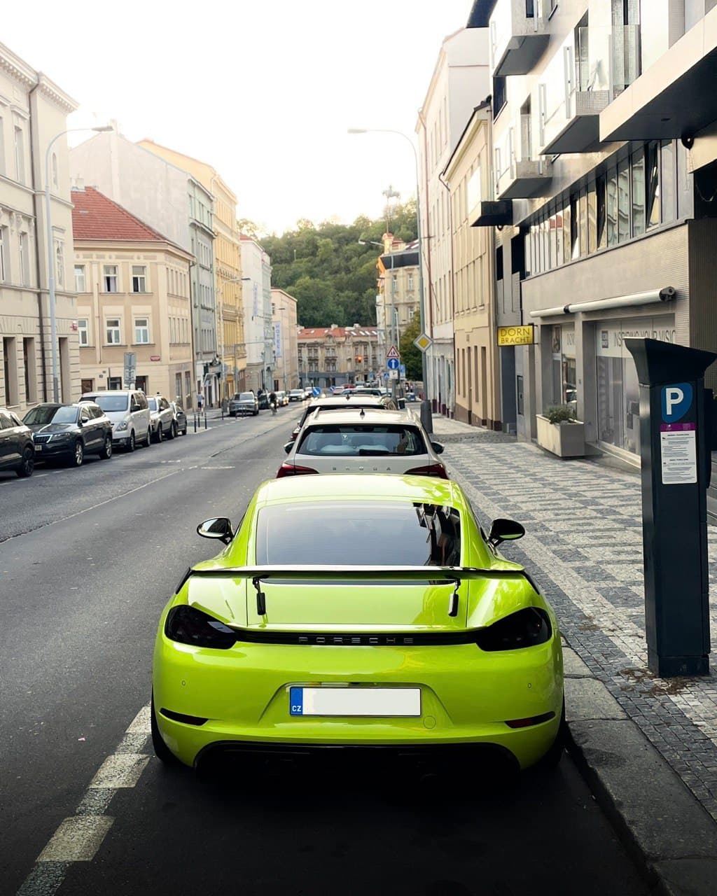 Vibrant neon yellow sports car parked on an urban street with a rear wing