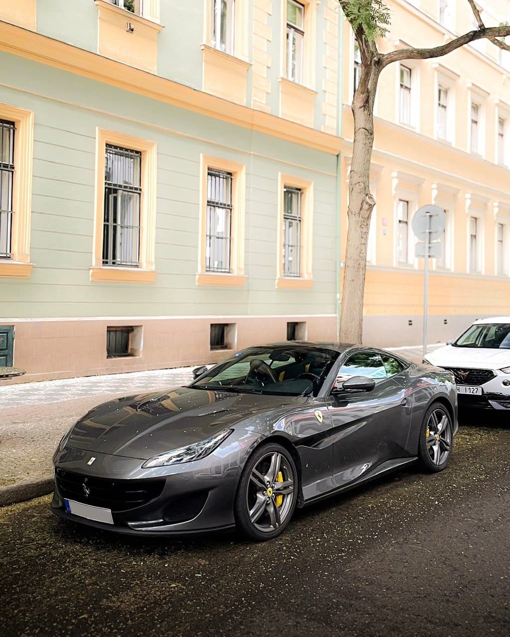 Grey Ferrari sports car parked on a historic European city street